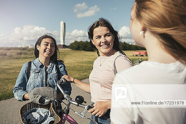 Smiling female teenager talking with each other at park during sunny day