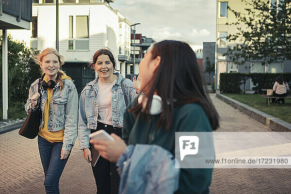 Glückliche weibliche Freunde  die miteinander reden  während sie auf dem Fußweg gehen