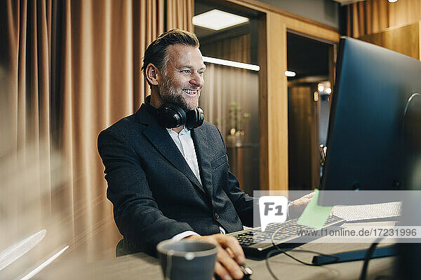 Lächelnder Geschäftsmann  der sich bei der Arbeit am Computer im Büro konzentriert