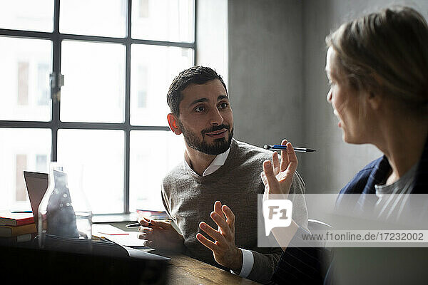 Female entrepreneur discussing with male colleague in creative office during meeting
