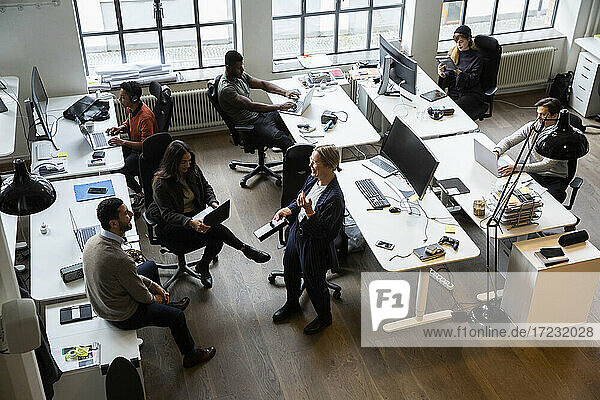 Geschäftsfrau lächelnd  während männliche und weibliche Kollegen arbeiten auf Laptop im Büro