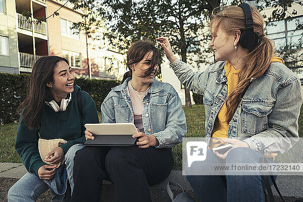 Weibliche Freunde mit digitalen Tablette sitzen im Park