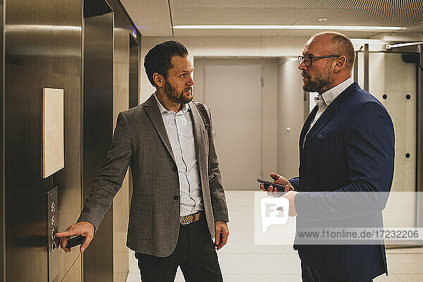 Businessmen talking near office elevator