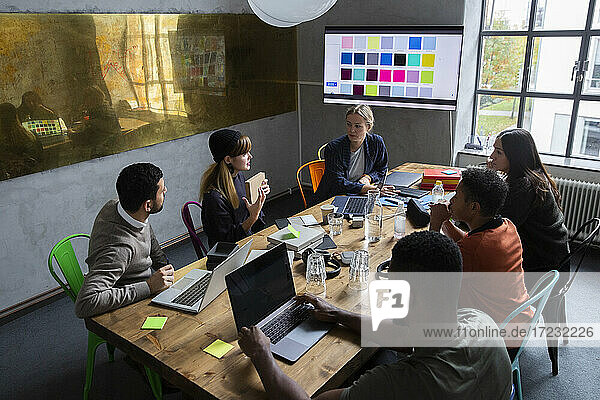 Unternehmerin erklärt Strategie des Produkts mit Kollegen am Schreibtisch im Konferenzraum