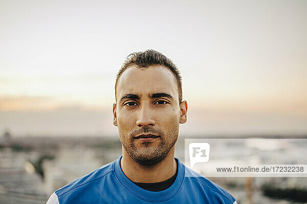 Portrait of confident male athlete against sky during sunset