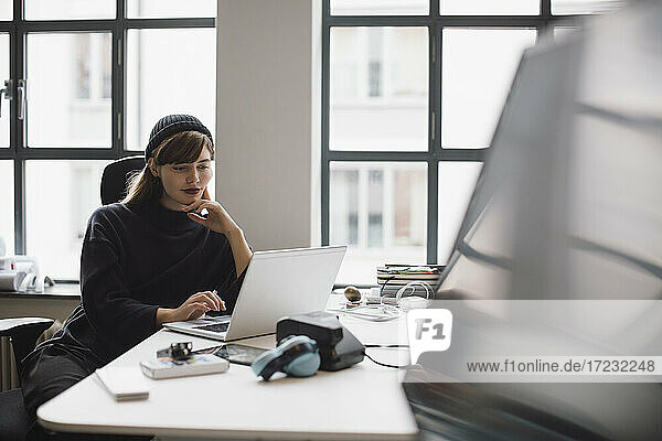 Weibliche Unternehmerin arbeitet am Laptop  während sie am Schreibtisch im Büro sitzt