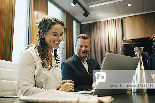 Smiling male and female lawyer discussing over laptop in office