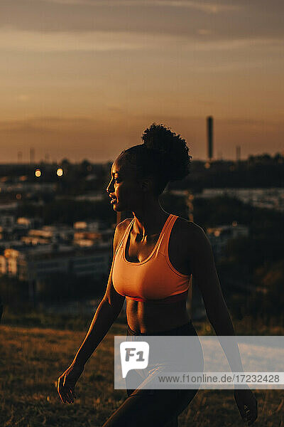 Weibliche Athletin schaut bei Sonnenuntergang weg