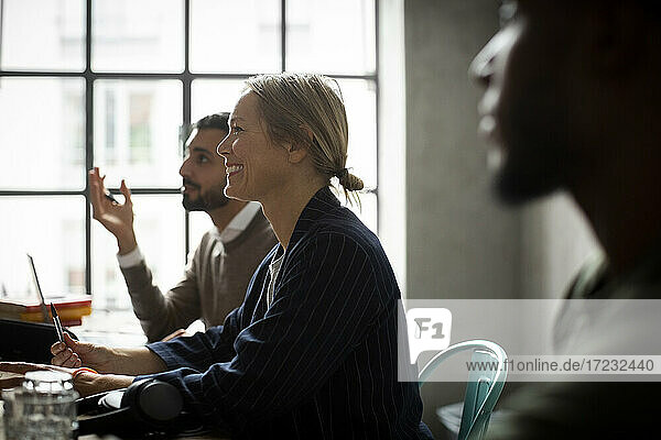 Happy male and female coworkers discussing while working in creative office