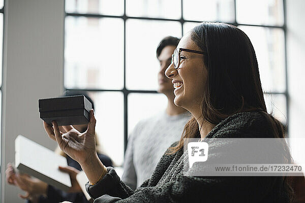 Smiling female entrepreneur with box discussing during meeting at creative office