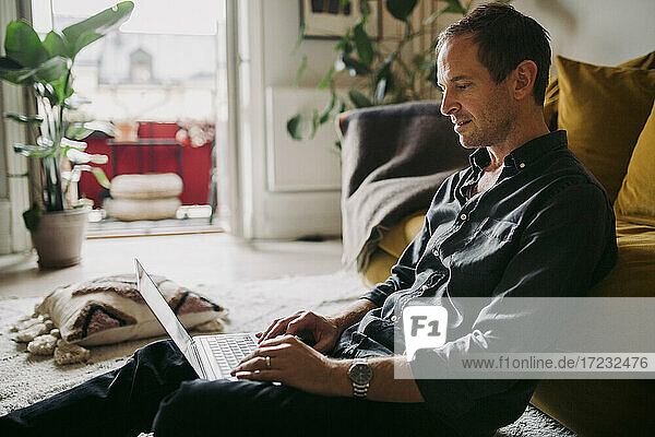 Male entrepreneur working on laptop in living room during pandemic