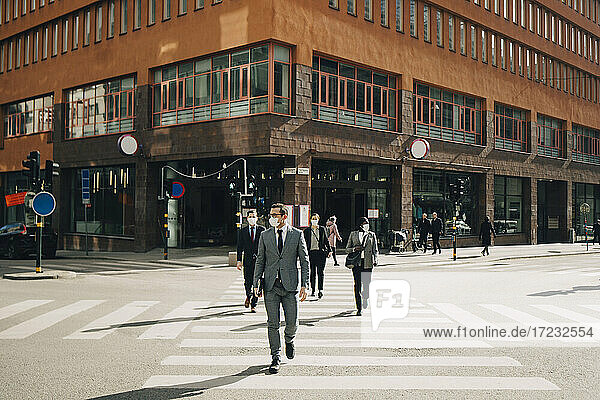 Business people crossing street on sunny day during COVID-19