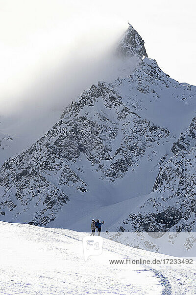 Touristen beim Fotografieren der verschneiten Gipfel während einer Winterwanderung  Muottas Muragl  Samedan  Engadin  Kanton Graubünden  Schweiz  Europa