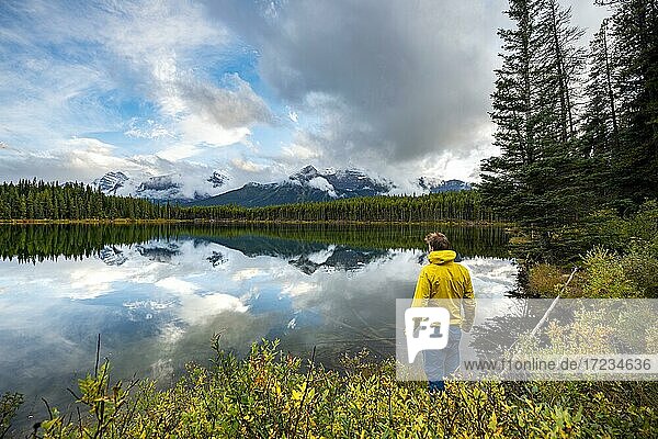 Hiker at the lakeside looking at mountains  autumnal Herbert Lake  mountains of the Bow Range reflected in the lake  Banff National Park  Canadian Rocky Mountains  Alberta  Canada  North America