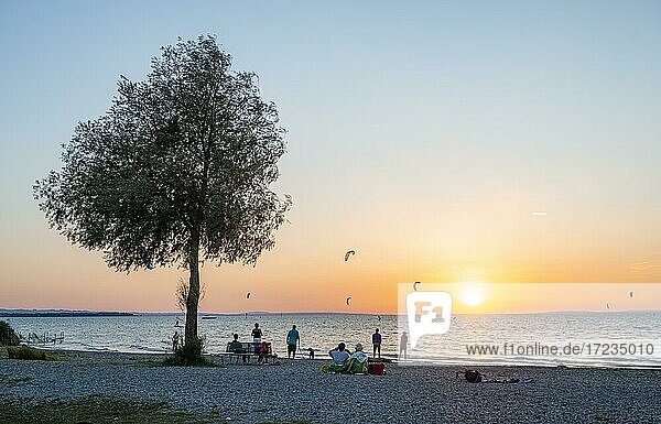 People on the shore of Lake Constance  kitesurfers in the lake  sunset  Bavaria  Germany  Europe