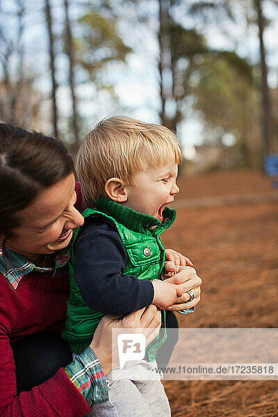 Lachende Mutter kitzelt Sohn im Park