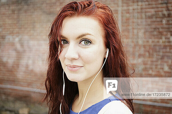 Porträt einer jungen Frau mit langen roten Haaren  die Kopfhörer trägt  Nahaufnahme