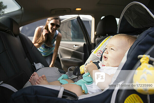 Mid adult woman checking safety belt on baby daughters car seat