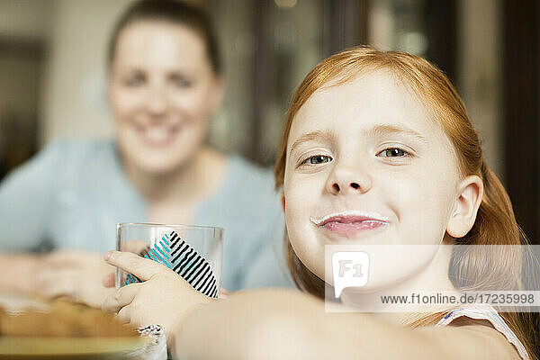 Girl with a milk moustache at dining room table