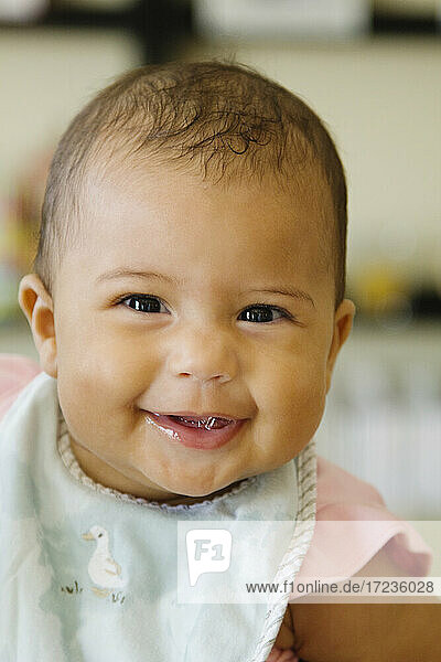 Porträt von Baby Mädchen trägt Lätzchen Blick auf die Kamera lächelnd