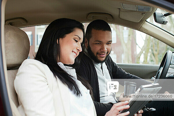 Young couple in car with digital tablet