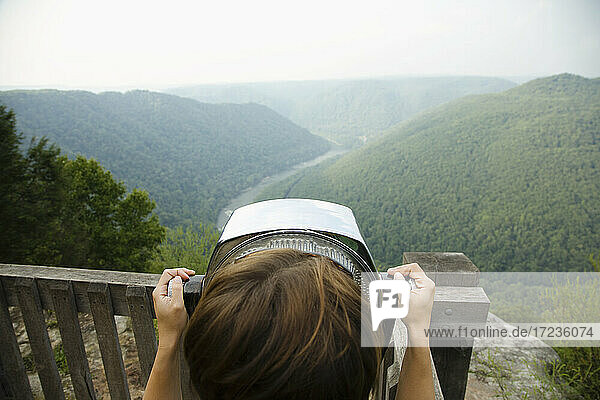 Mittlere erwachsene Frau schaut durch ein münzbetriebenes Fernglas  Rückansicht  New River Gorge National River  Fayetteville  West Virginia  USA