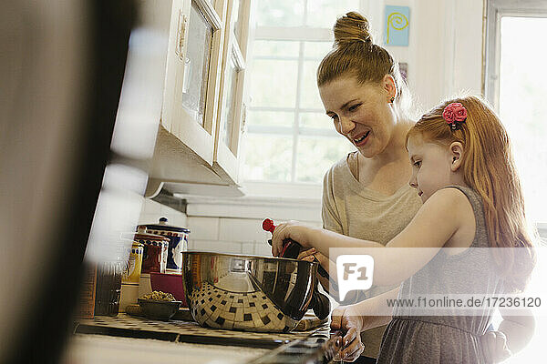 Mid erwachsene Mutter gibt Tochter eine helfende Hand in der Küche