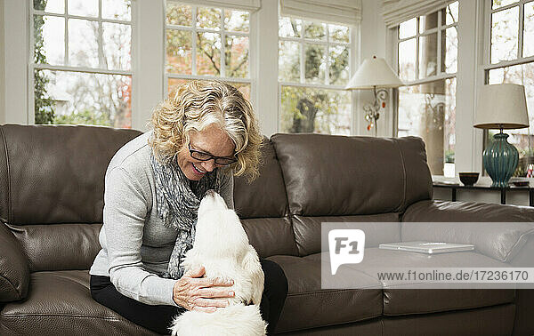 Ältere Frau mit Labradorhund im Wohnzimmer