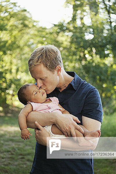 Vater im Freien hält und küsst Baby Mädchen
