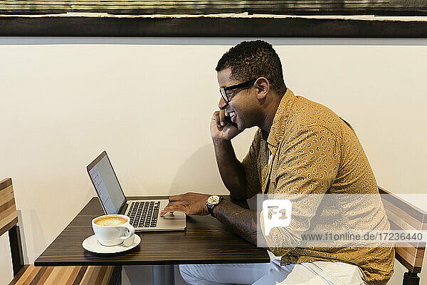 Junger Mann im Café  mit Laptop und Smartphone