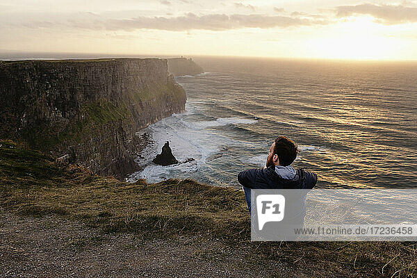 Mid adult man sitting on The Cliffs of Moher  The Burren  County Clare  Ireland