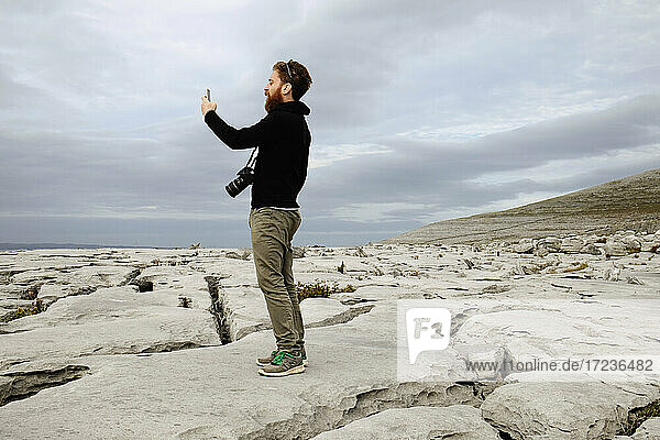 Mid adult man taking photo on phone  The Burren  County Clare  Ireland