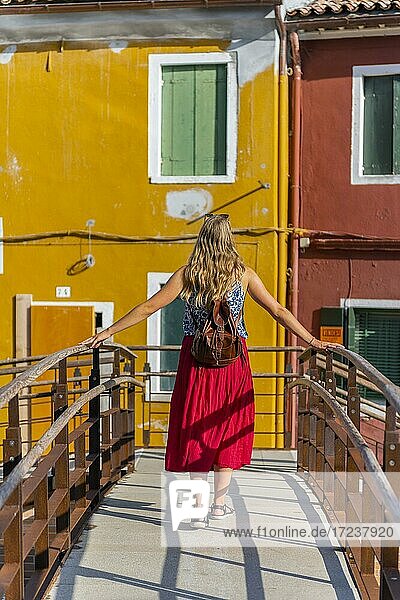 Junge Frau vor bunten Häusern  farbenprächtige Häuserfassaden  Insel Burano  Venedig  Venetien  Italien  Europa