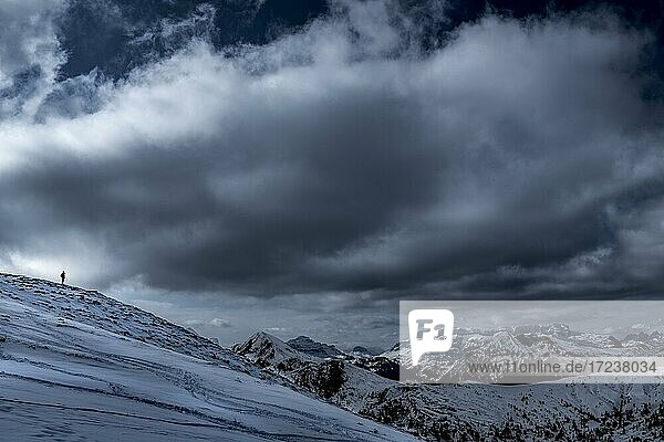 Photographer on ridge with dramatic cloudy sky  Zoldo Alto  Val di Zoldo  Dolomites  Italy  Europe