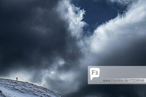 Photographer on ridge with dramatic cloudy sky  Zoldo Alto  Val di Zoldo  Dolomites  Italy  Europe