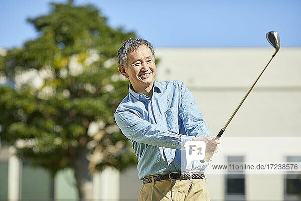 Senior Japanese man playing golf at home