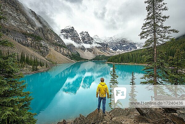 Young man looking at mountains  cloudy mountain peaks  reflection in turquoise glacial lake  Moraine Lake  Valley of the Ten Peaks  Rocky Mountains  Banff National Park  Alberta Province  Canada  North America