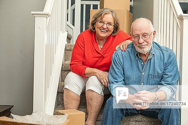Älteres Paar ruht sich auf einer Treppe aus  umgeben von Umzugskartons