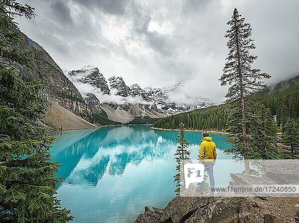 Young man looking at mountains  cloudy mountain peaks  reflection in turquoise glacial lake  Moraine Lake  Valley of the Ten Peaks  Rocky Mountains  Banff National Park  Alberta Province  Canada  North America