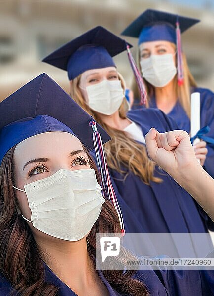 Mehrere Absolventinnen in Kappe und Talar mit medizinischen Gesichtsmasken