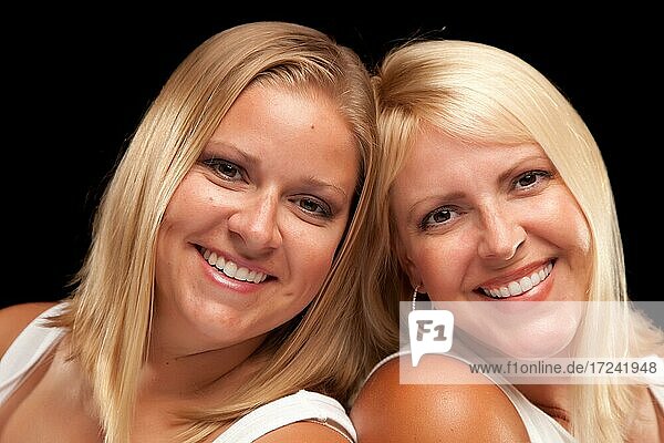 Two beautiful smiling sisters portrait isolated on a black background