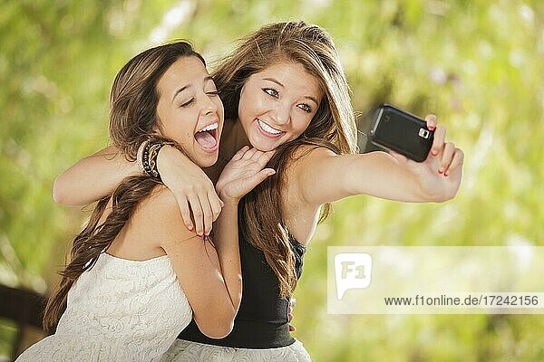 Zwei attraktive gemischtrassige Freundinnen machen Selfie mit Handy im Freien