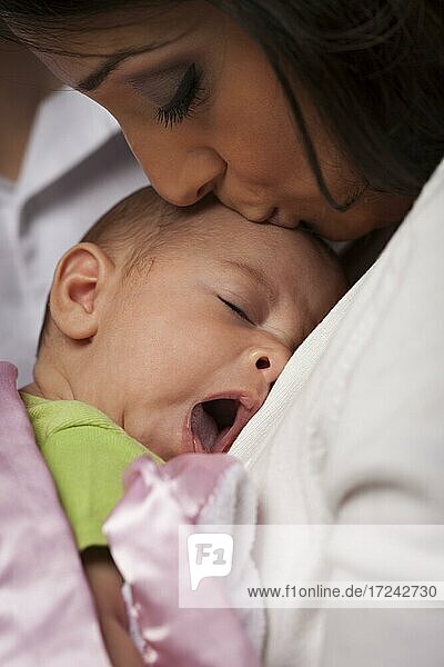 Junge attraktive ethnische Frau hält ihr gähnendes neugeborenes Baby