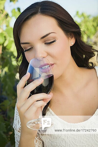 Hübsche multiethnische junge Frau genießt ein Glas Wein im Weinberg