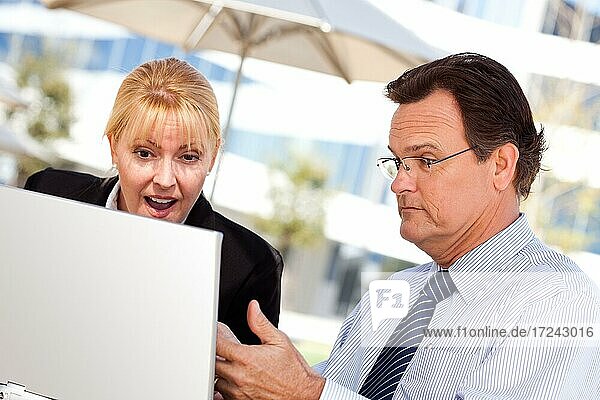 Handsome businessman working on the laptop with attractive female colleague outdoors