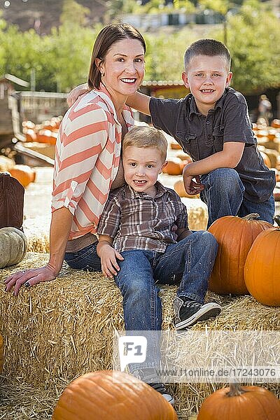 Attractive mother and her two sons pose for a portrait in a rustic ranch setting at the pumpkin patch
