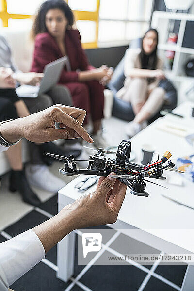 Männliche Ingenieure erläutern das Drohnenmodell mit Kollegen im Büro