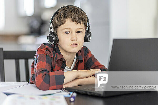 Junge mit Kopfhörern beim E-Learning  während er zu Hause am Laptop sitzt