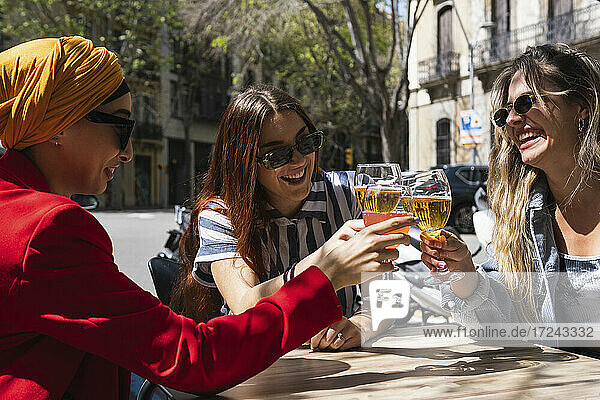 Cheerful female friends toasting glasses during sunny day