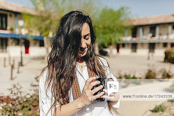 Lächelnde Touristin mit Kamera in der Hand an einem sonnigen Tag